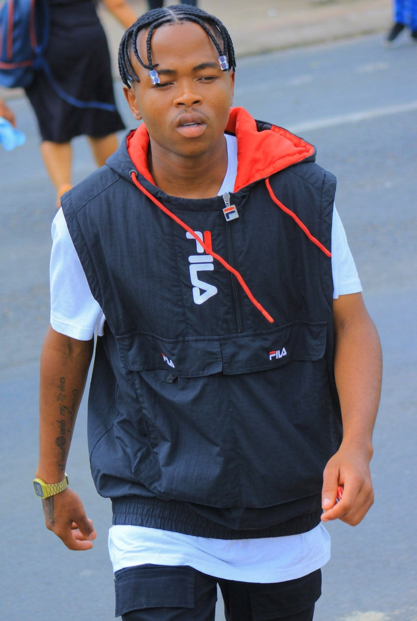 LatshuZAR wearing a black and red FILA vest