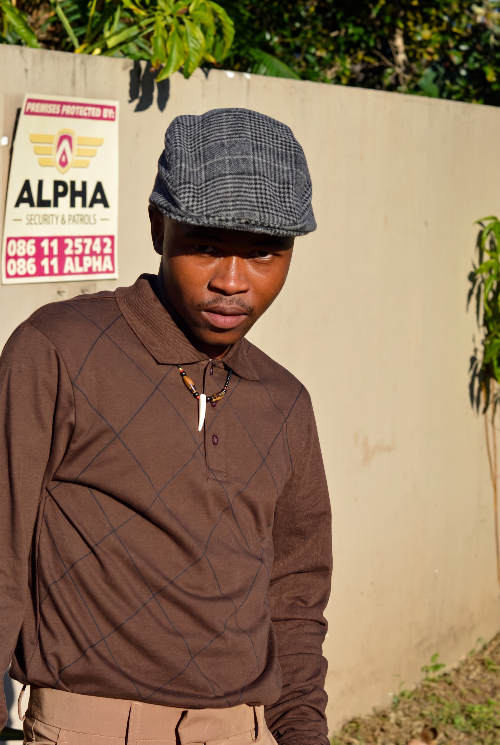 LatshuZAR in a brown polo and flat cap